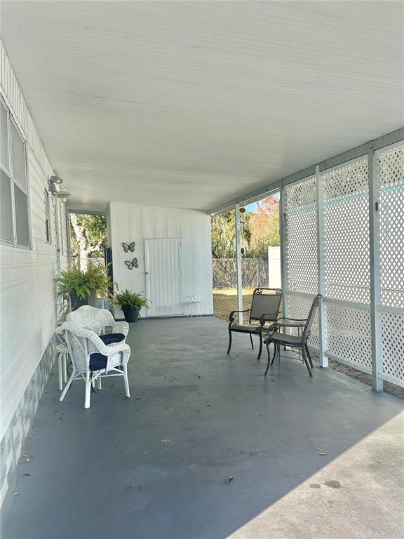 A covered outdoor patio features a concrete floor, white lattice walls, and several chairs — 5619 BAYSHORE ROAD UNIT 328, PALMETTO, FL