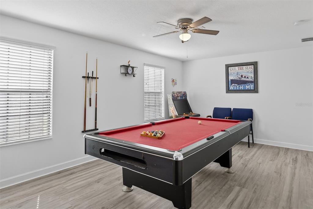 A game room features a pool table, a wall-mounted cue rack, and a nautical-themed wall print — 9107 EL CARO LANE, DAVENPORT, FL