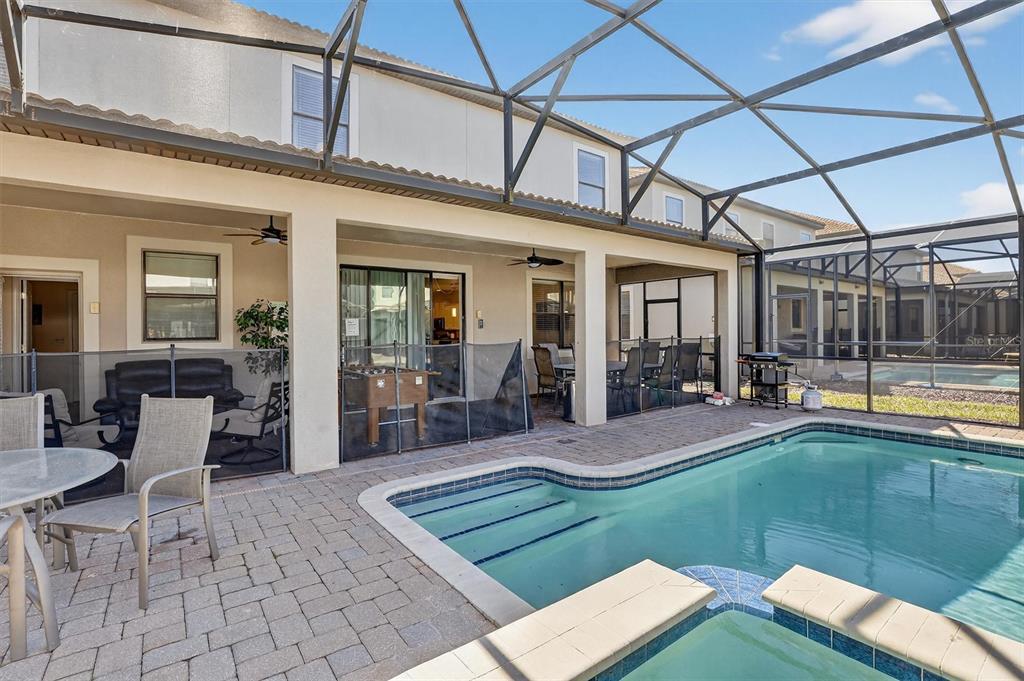 A screened-in patio features a swimming pool, a hot tub, and outdoor furniture — 9107 EL CARO LANE, DAVENPORT, FL