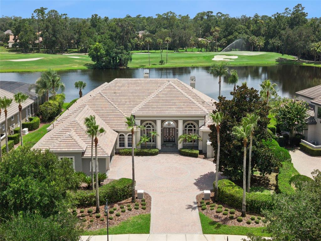 An aerial view of a single-story house with a circular driveway, tile roof, and lakefront — 4013 BERMUDA GROVE PLACE, LONGWOOD, FL