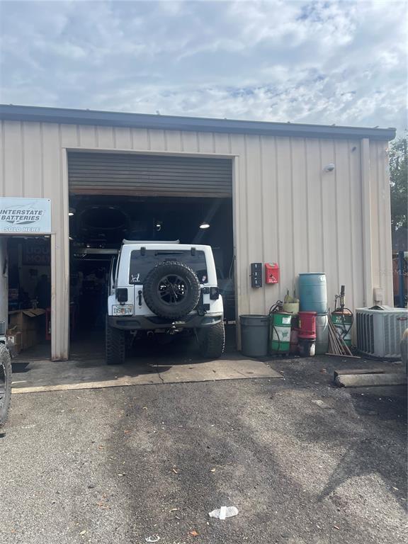 A white Jeep is parked in the open bay of a metal-sided commercial garage — 30940 SUNEAGLE DRIVE UNIT 105, MOUNT DORA, FL