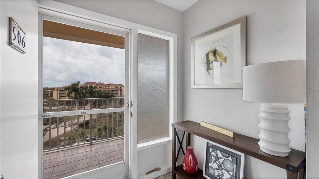 An entryway features a glass door leading to a balcony, a console table, and artwork — 8625 MIDNIGHT PASS ROAD UNIT 506B, SARASOTA, FL