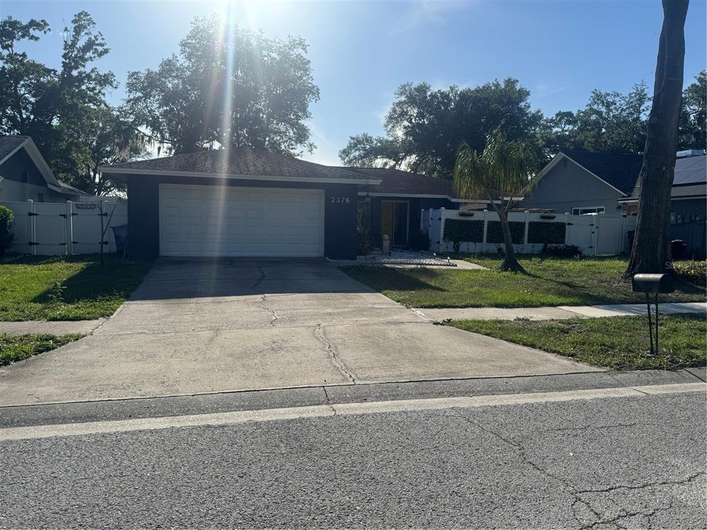 A single-story house with a white garage door, a concrete driveway, and a fenced yard — 2376 WINDSOR OAKS AVENUE, LUTZ, FL