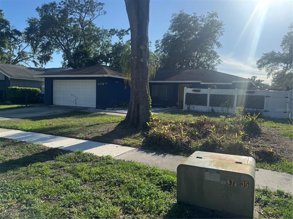 A dark blue single-story house with a two-car garage and a white privacy fence — 2376 WINDSOR OAKS AVENUE, LUTZ, FL