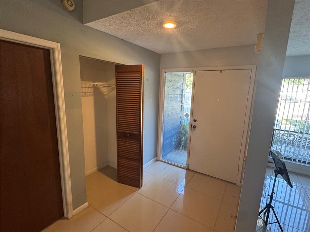 An entryway with light tile flooring, a closet with louvered doors, and a white front door — 2376 WINDSOR OAKS AVENUE, LUTZ, FL