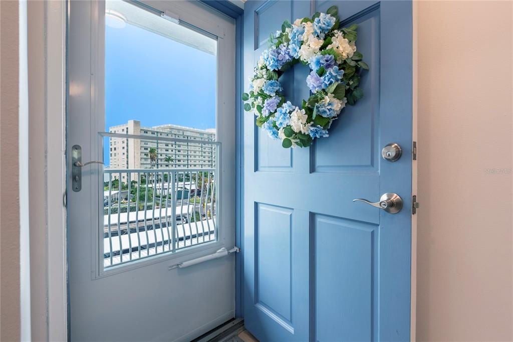 An open blue front door with a floral wreath leads into a residential unit — 5925 SHORE BOULEVARD S UNIT 405, GULFPORT, FL