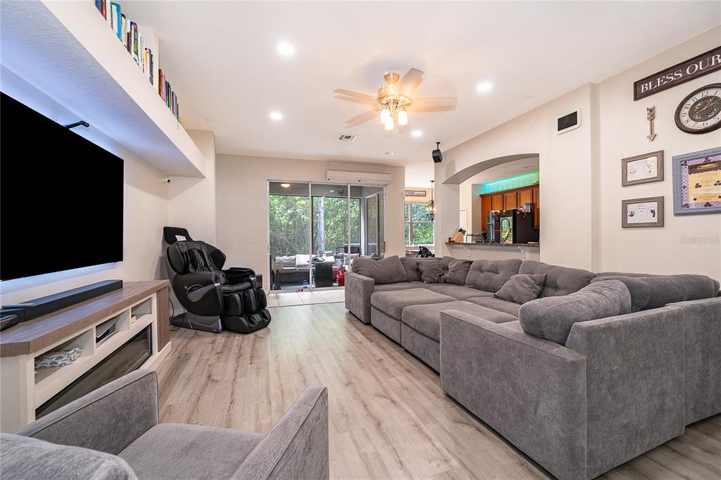 A living room features a large gray sectional, a massage chair, and a wall-mounted television — 9808 BENNINGTON CHASE DRIVE, ORLANDO, FL