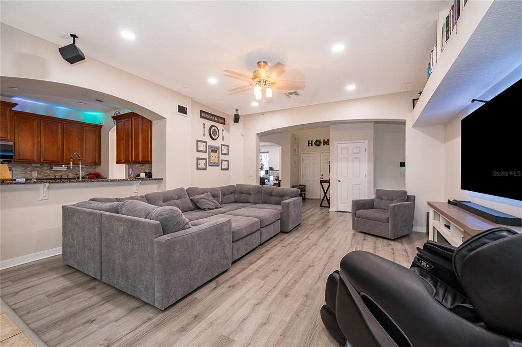 A living room features a large gray sectional sofa, a television, and wood-look flooring — 9808 BENNINGTON CHASE DRIVE, ORLANDO, FL