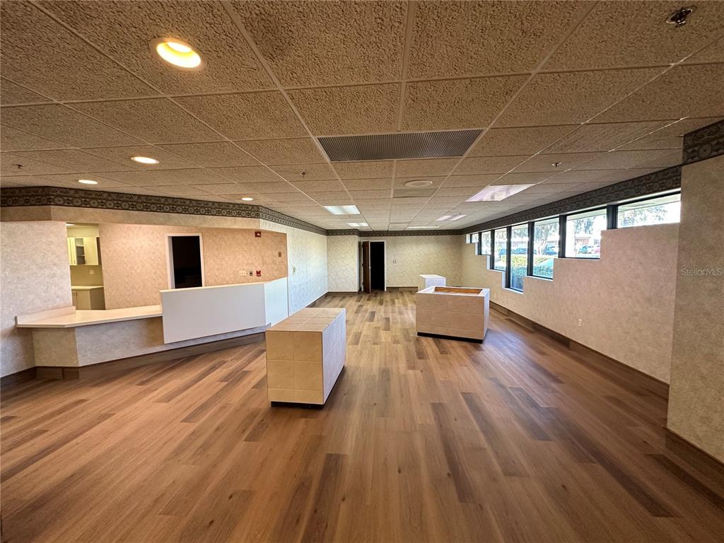 An empty commercial space features wood-look flooring, a drop ceiling, and a built-in reception desk — 640 S LAKE STREET, LEESBURG, FL