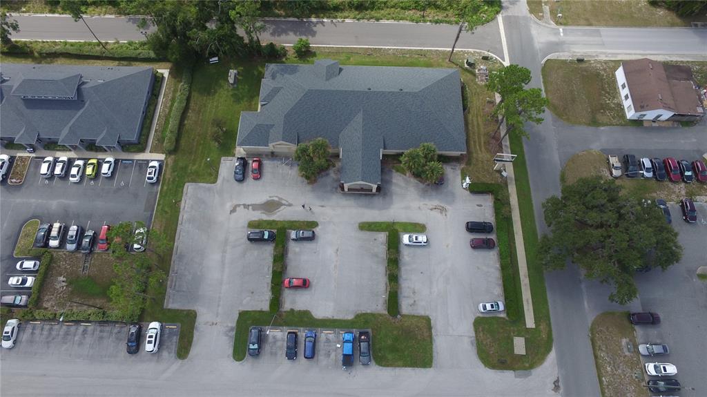 An aerial view shows a commercial building with a large parking lot and surrounding trees — 640 S LAKE STREET, LEESBURG, FL