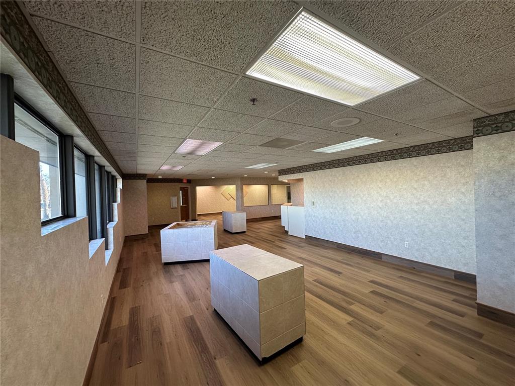 An empty commercial office space with wood-look flooring, tiled display islands, and drop ceilings — 640 S LAKE STREET, LEESBURG, FL
