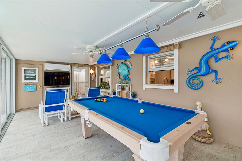 A sunroom features a blue pool table, blue pendant lighting, and decorative wall art — 5843 APPLETREE ROAD, HOLIDAY, FL