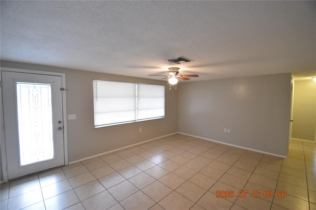 A living room with light-colored tile flooring, beige walls, and a ceiling fan — 3221 TOPP DRIVE, HOLIDAY, FL