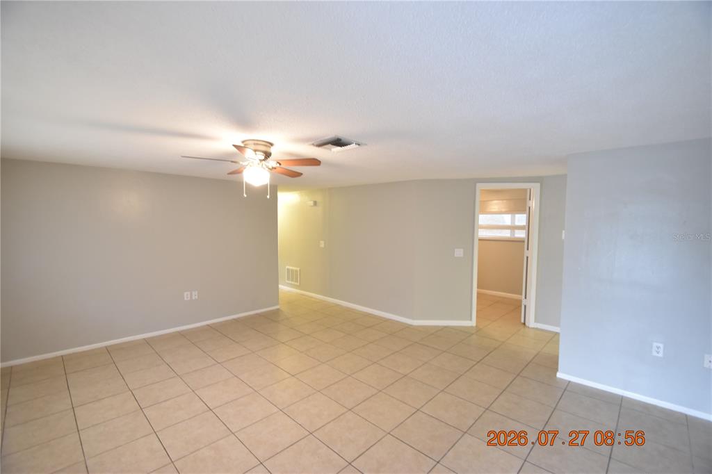 An empty room features light-colored walls, a ceiling fan, and beige tile flooring — 3221 TOPP DRIVE, HOLIDAY, FL