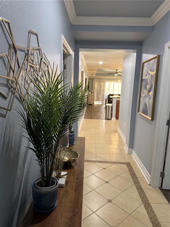 A hallway with tile flooring leads toward an open living area with a ceiling fan — 7601 CABANA COURT UNIT 103, REUNION, FL