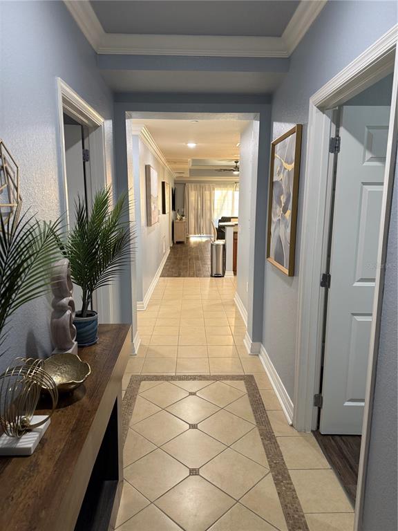 A hallway with light blue walls, tile flooring, and a console table leads to a living area — 7601 CABANA COURT UNIT 103, REUNION, FL