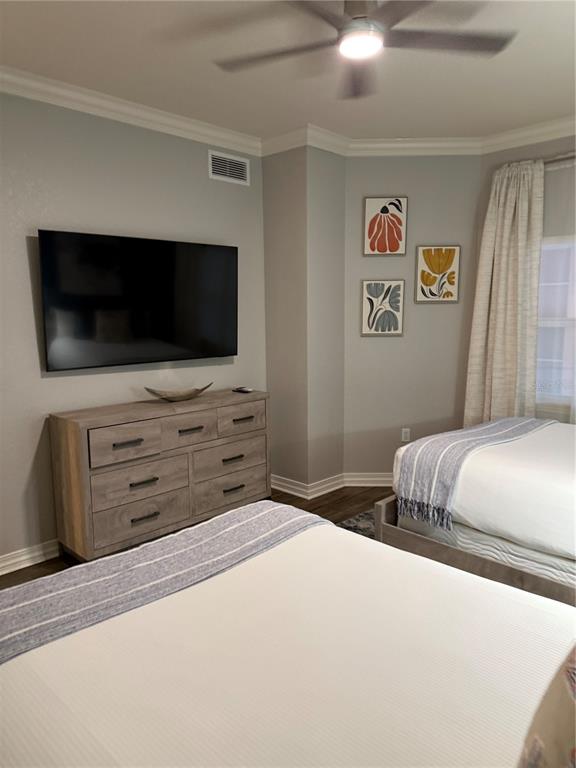 A bedroom features two beds, a wooden dresser, a wall-mounted television, and framed wall art — 7601 CABANA COURT UNIT 103, REUNION, FL