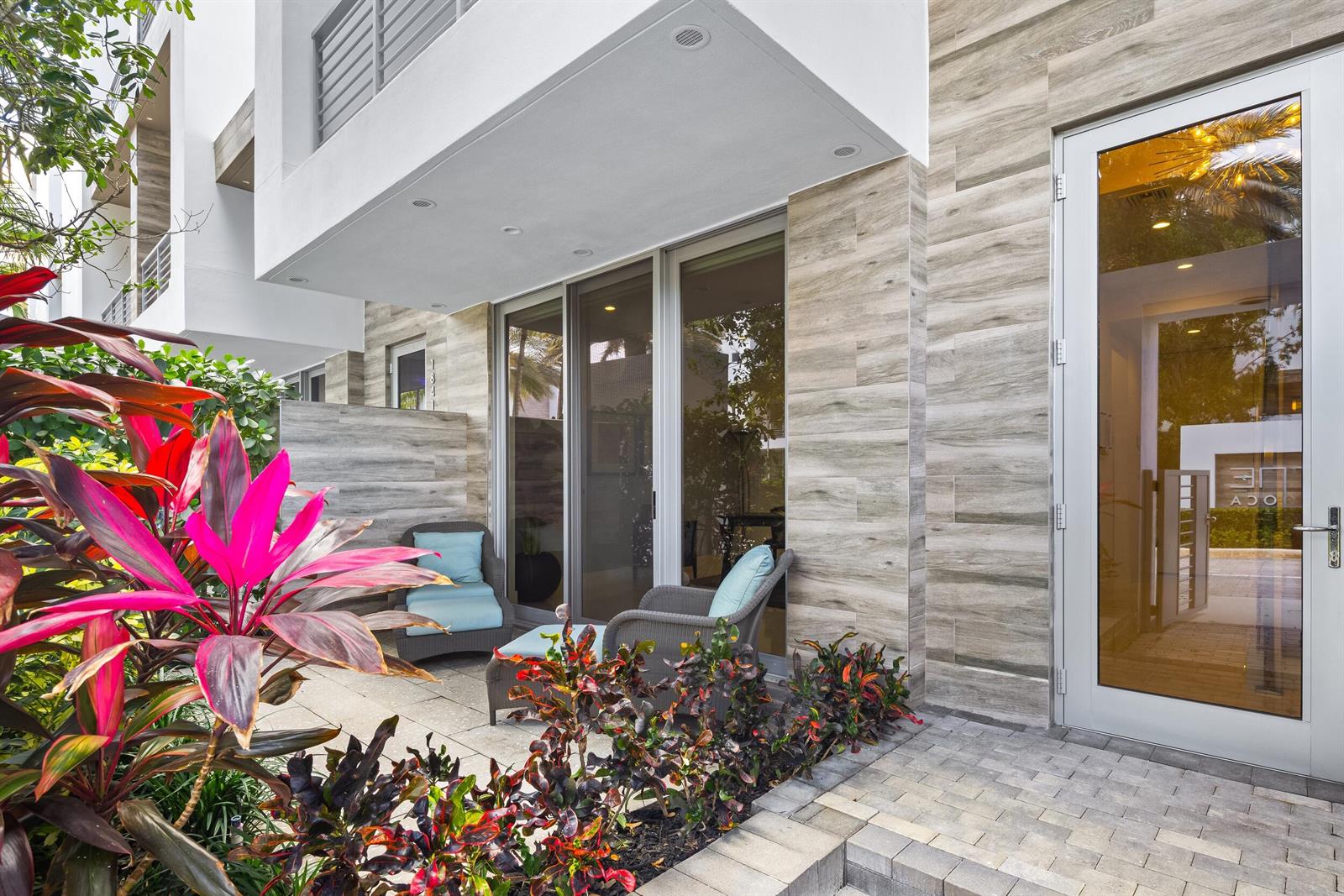 A patio with two chairs sits outside a building featuring wood-look tile siding — 1851 NW 40th Drive, Boca Raton FL 33431, BOCA RATON, FL
