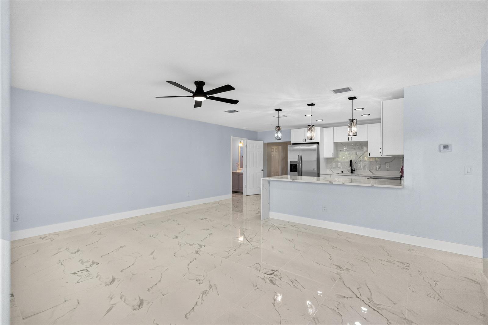An open-concept living area features light blue walls, white cabinets, and white marble-patterned tile flooring — 1531 NE 33rd Street, Pompano Beach FL 33064, POMPANO BEACH, FL