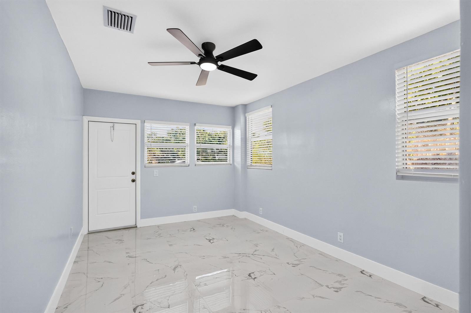 A room with light blue walls, white trim, marble-look tile flooring, and a ceiling fan — 1531 NE 33rd Street, Pompano Beach FL 33064, POMPANO BEACH, FL