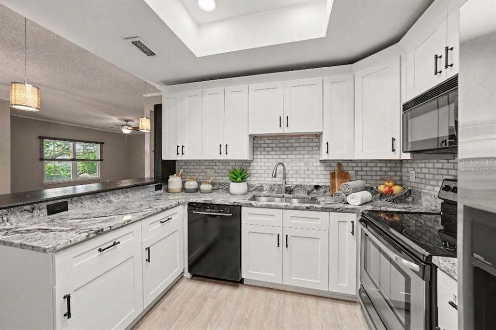 A kitchen with white cabinets, granite countertops, a subway tile backsplash, and stainless steel appliances — 8350 SAVANNAH TRACE CIRCLE UNIT 106, TAMPA, FL