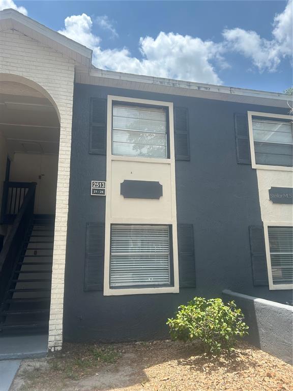 The exterior of a two-story apartment building features dark gray stucco and white brick accents — 2513 N ALAFAYA TRAIL UNIT 21, ORLANDO, FL