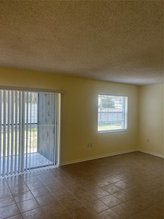 An empty room with light yellow walls, tile flooring, a sliding glass door, and windows — 2513 N ALAFAYA TRAIL UNIT 21, ORLANDO, FL