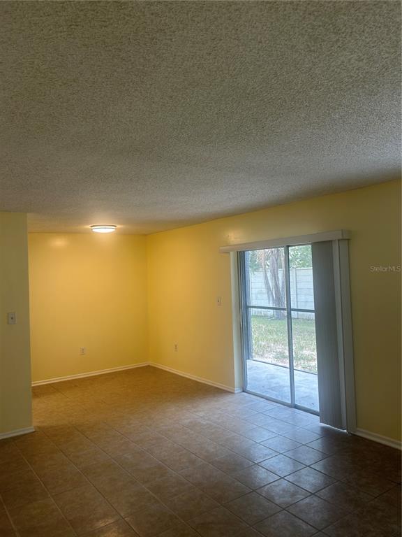 An empty room with yellow walls, tile flooring, and a sliding glass door to outside — 2513 N ALAFAYA TRAIL UNIT 21, ORLANDO, FL