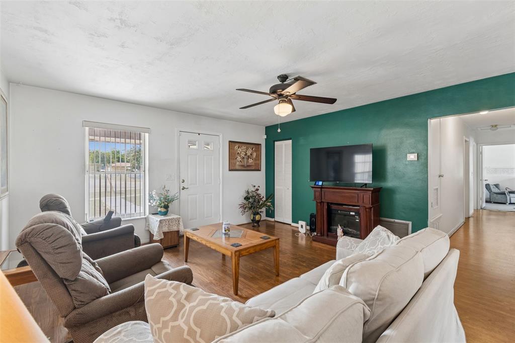 A living room features a green accent wall, a fireplace, and light-colored furniture — 6395 TREEHAVEN DRIVE, SPRING HILL, FL