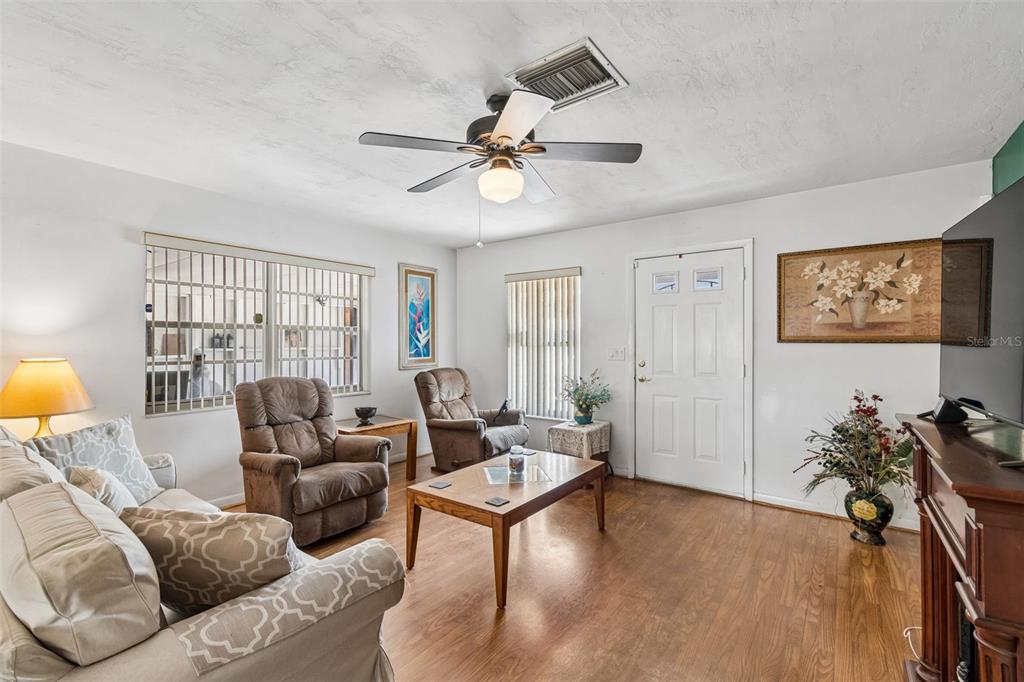 A living room features a dark green accent wall, a fireplace, and neutral-toned furniture — 6395 TREEHAVEN DRIVE, SPRING HILL, FL