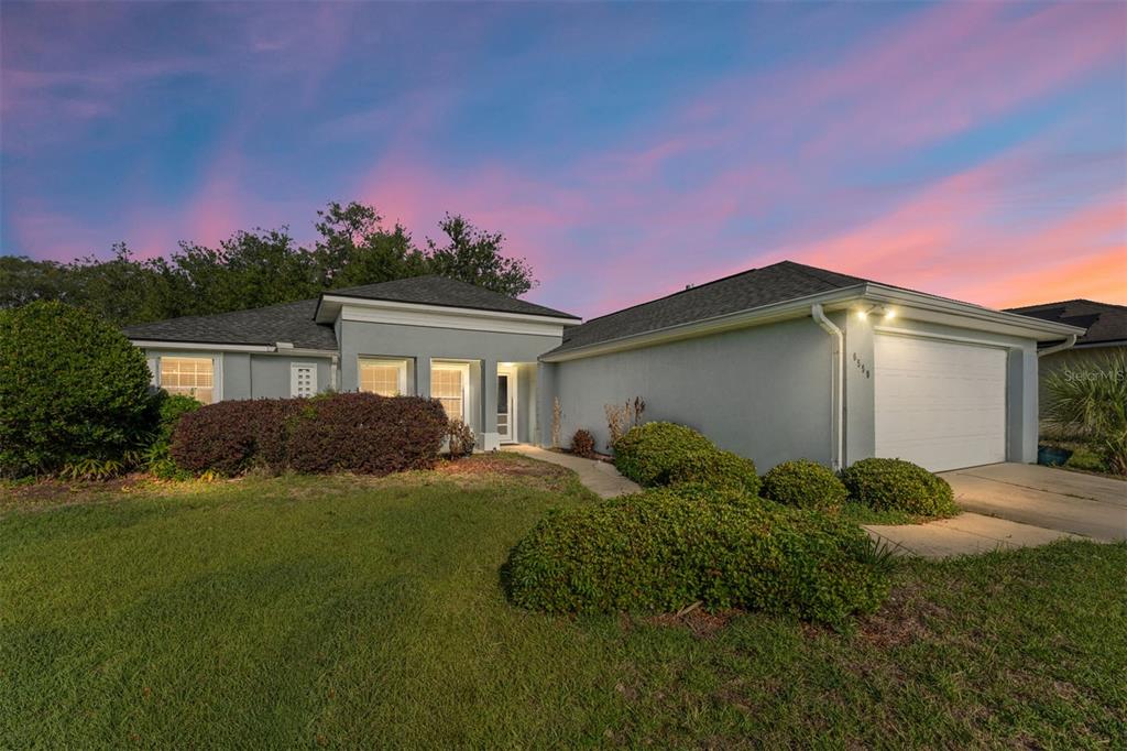 A single-story house with a gray exterior, a two-car garage, and a landscaped front yard — 6550 SW 50TH COURT, OCALA, FL