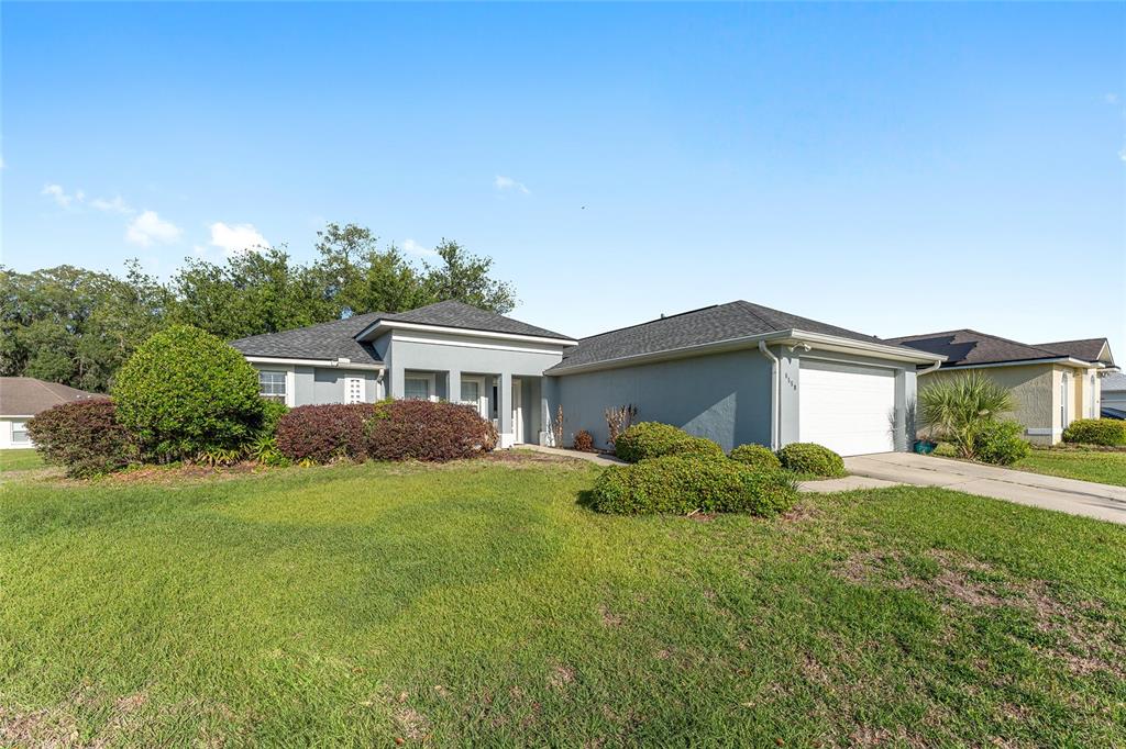 A single-story house with a gray exterior, a two-car garage, and landscaped front yard — 6550 SW 50TH COURT, OCALA, FL