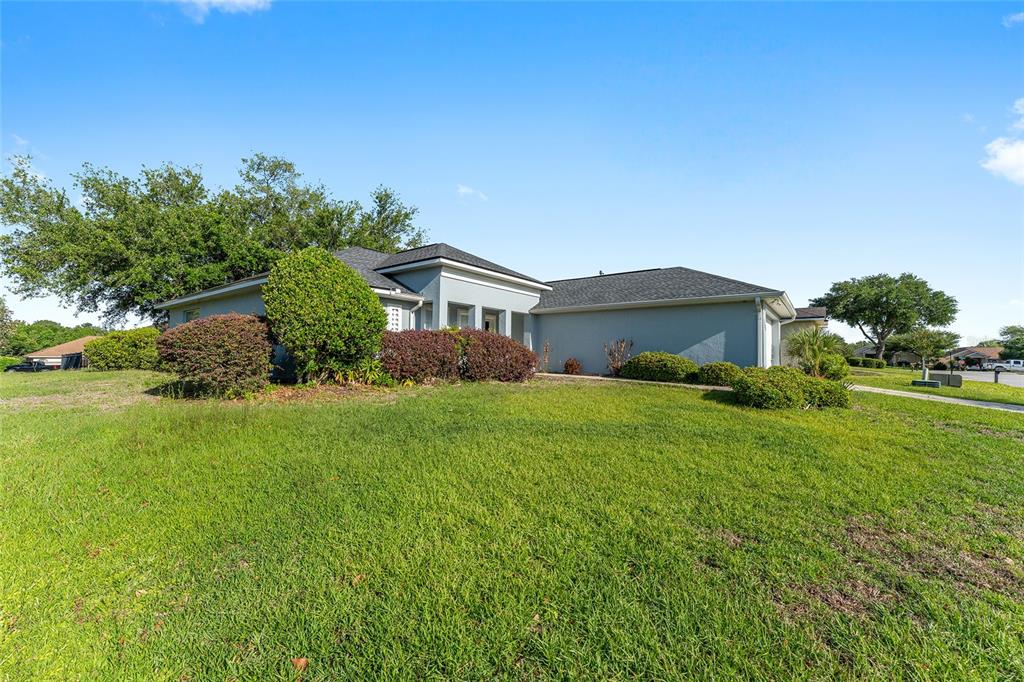 A single-story house with a gray exterior, dark roof, and landscaped bushes on a lawn — 6550 SW 50TH COURT, OCALA, FL