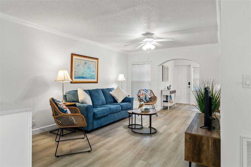 A living room features a blue sofa, wood-look flooring, and a ceiling fan — 19417 GULF BOULEVARD UNIT C106, INDIAN ROCKS BEACH, FL