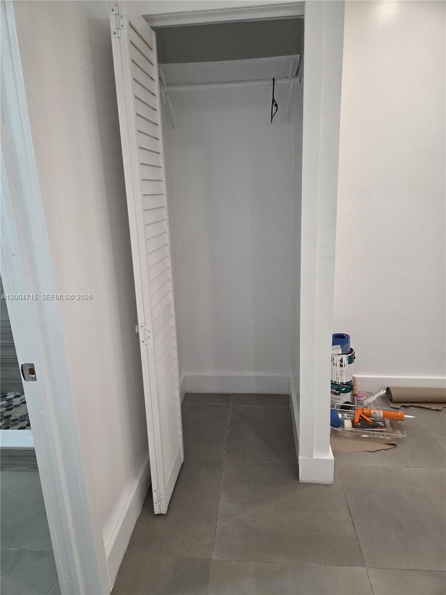 A small closet with louvered doors and a hanging rod sits in a tiled room — 6335 N Miami Ave # 3, Miami FL 33150, MIAMI, FL
