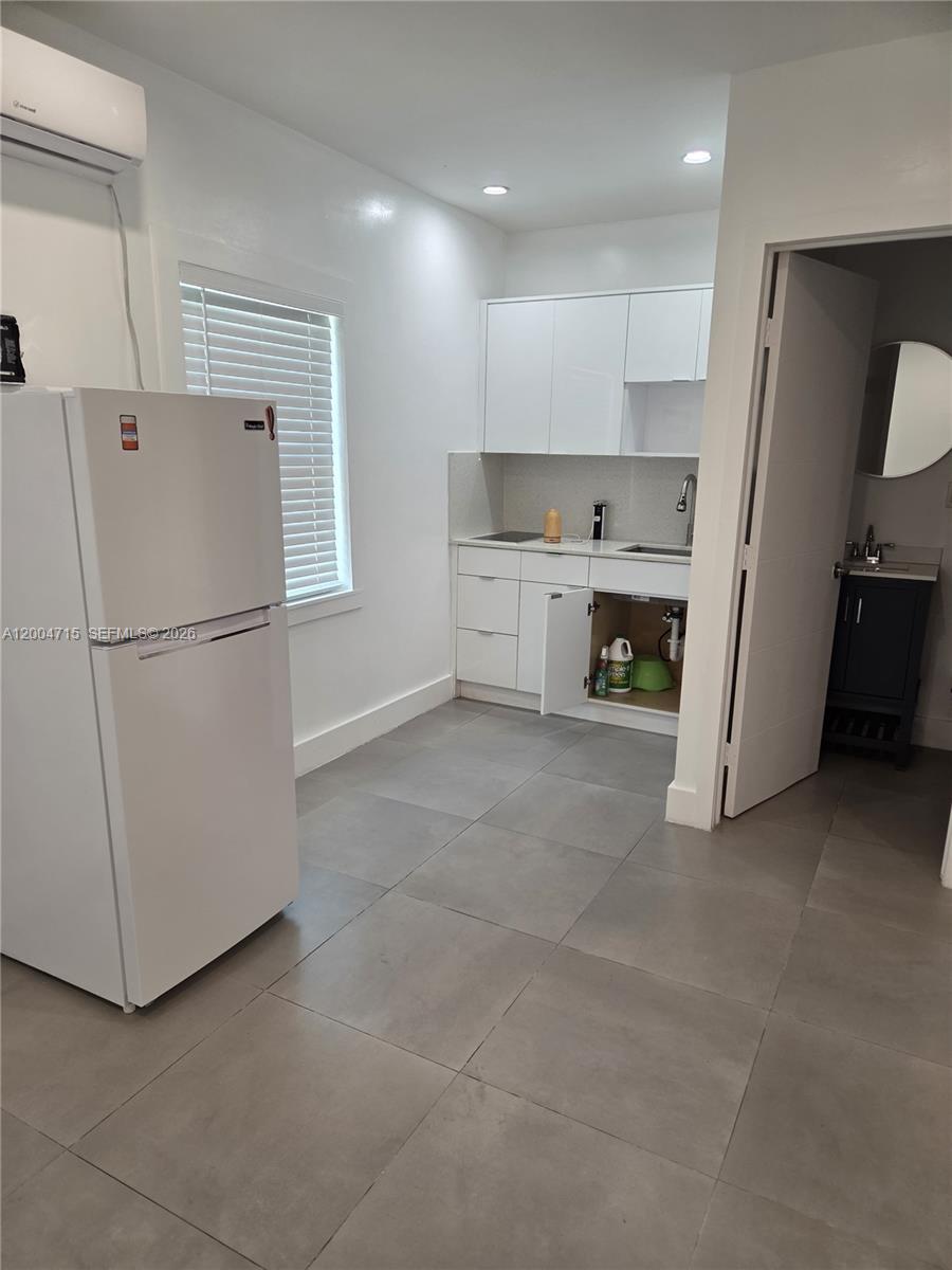 A small kitchen features white cabinets, a white refrigerator, and gray tile flooring — 6335 N Miami Ave # 3, Miami FL 33150, MIAMI, FL