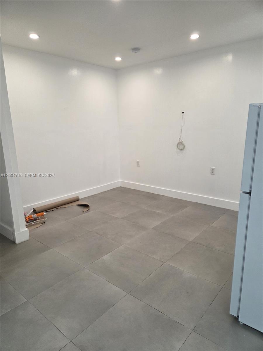 This empty room features white walls, recessed lighting, and large gray floor tiles — 6335 N Miami Ave # 3, Miami FL 33150, MIAMI, FL