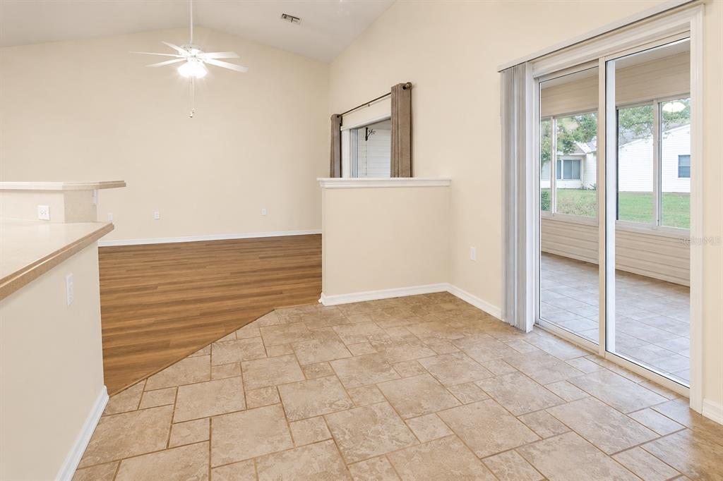 An interior view showing a tiled dining area, wood-look flooring, and a sliding glass door — 6032 MAGPIE DRIVE, LAKELAND, FL