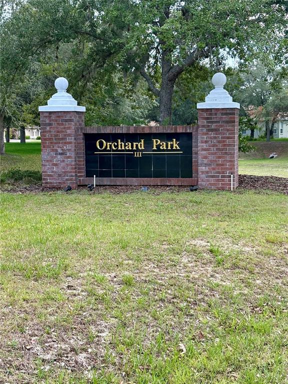 A brick entrance sign for Orchard Park III stands in a grassy lawn — 9925 REINDEER COURT, SPRING HILL, FL