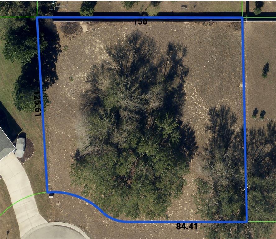 An aerial view shows a vacant, tree-covered residential lot with marked property boundaries — 9925 REINDEER COURT, SPRING HILL, FL