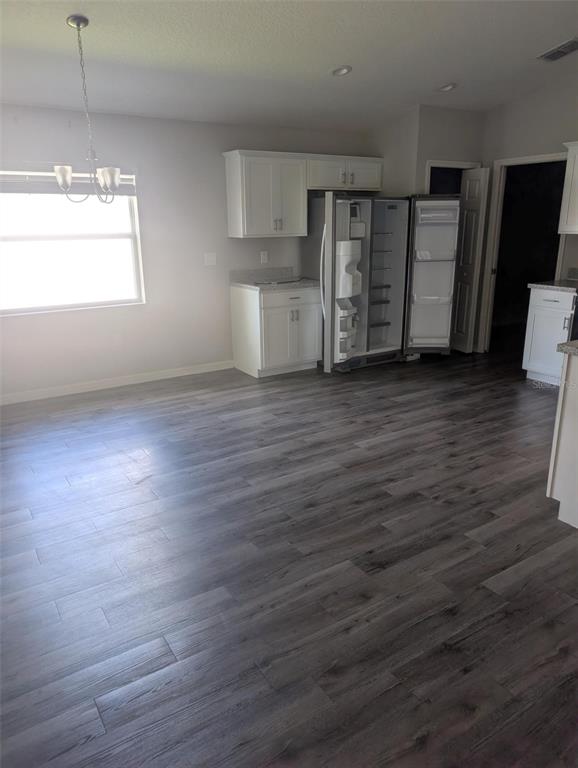 A kitchen area features white cabinets, a stainless steel refrigerator, and gray wood-look flooring — 3902 WHITE IBIS ROAD, LAKELAND, FL