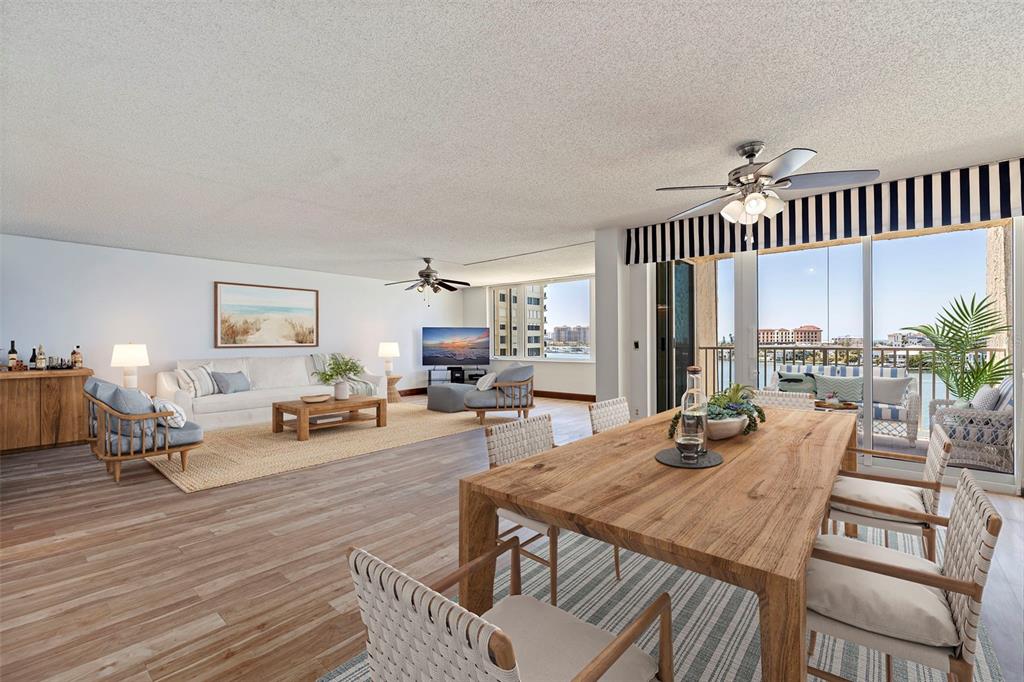 An open-concept living and dining area features wood-look flooring, ceiling fans, and a balcony view — 736 ISLAND WAY UNIT 504, CLEARWATER BEACH, FL