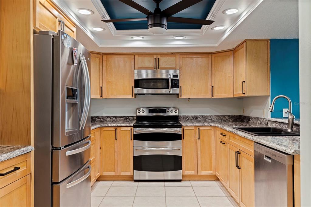 A kitchen with light wood cabinets, stainless steel appliances, granite countertops, and a blue ceiling — 736 ISLAND WAY UNIT 504, CLEARWATER BEACH, FL