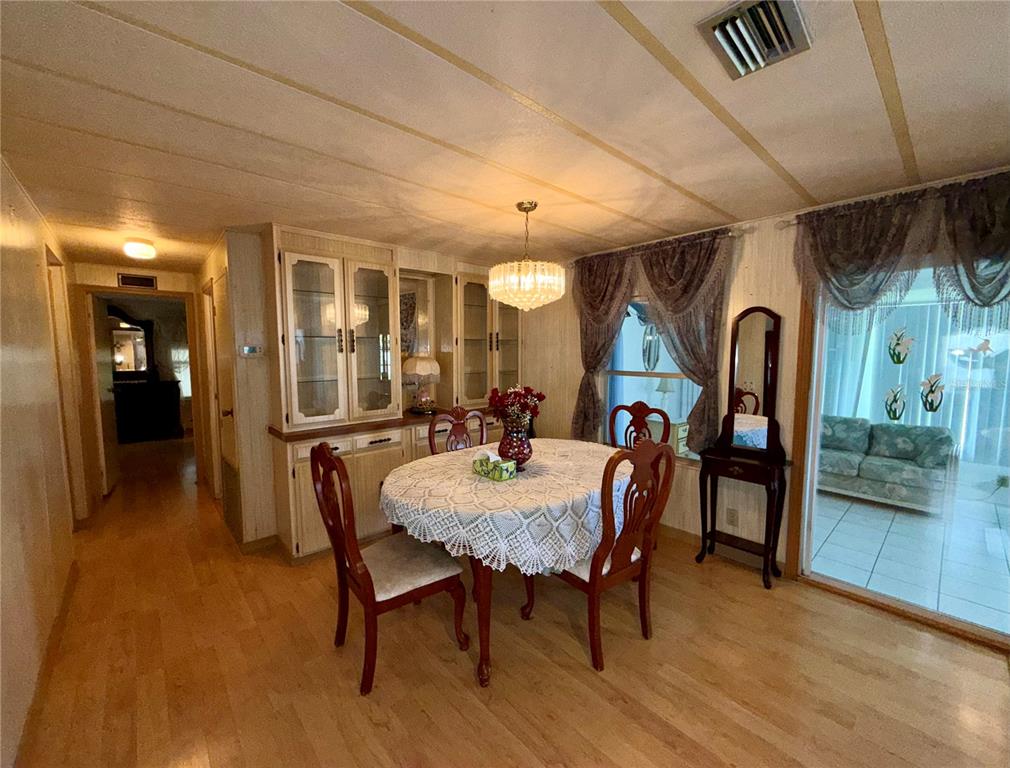A dining area features a round table, wooden chairs, a built-in hutch, and wood flooring — 82167 D STREET N UNIT 167, PINELLAS PARK, FL