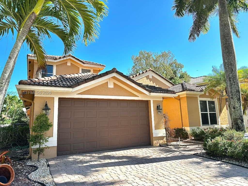 The exterior of a two-story house features a brown garage door and a paved driveway — 1831 Mariners Ln, Weston FL 33327, WESTON, FL