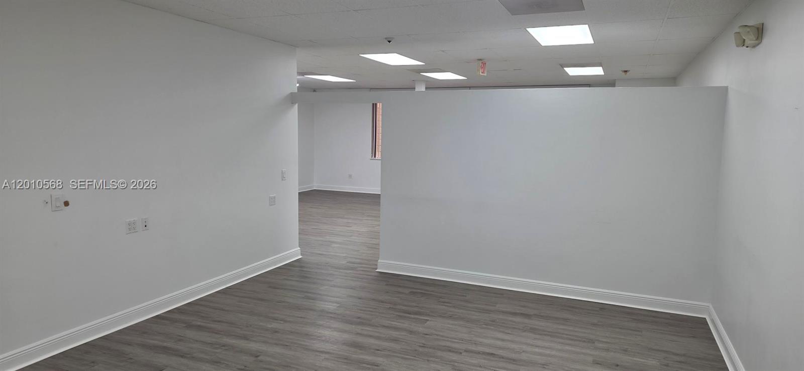 An empty office space features white walls, gray wood-look flooring, and recessed ceiling lights — 4503 NW 103rd Ave # 104, Sunrise FL 33351, SUNRISE, FL