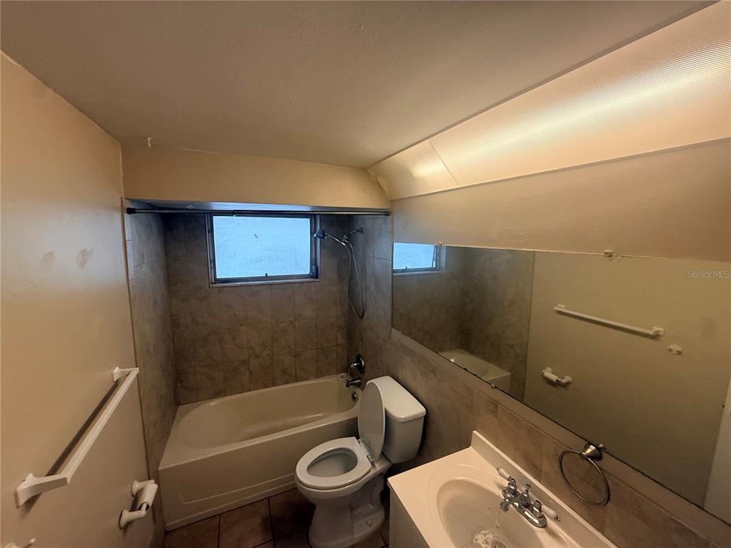 A bathroom features a tiled tub-shower combination, a toilet, and a large wall mirror — 3524 BRADFORD DRIVE, HOLIDAY, FL