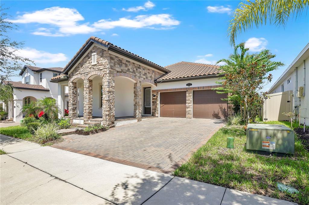 A single-story house with a stone facade, arched entryway, and a two-car garage — 8318 VIVARO ISLE WAY, WINDERMERE, FL