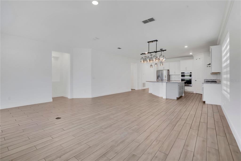 An open-concept living area features light wood-look tile flooring and a modern kitchen with island — 8318 VIVARO ISLE WAY, WINDERMERE, FL