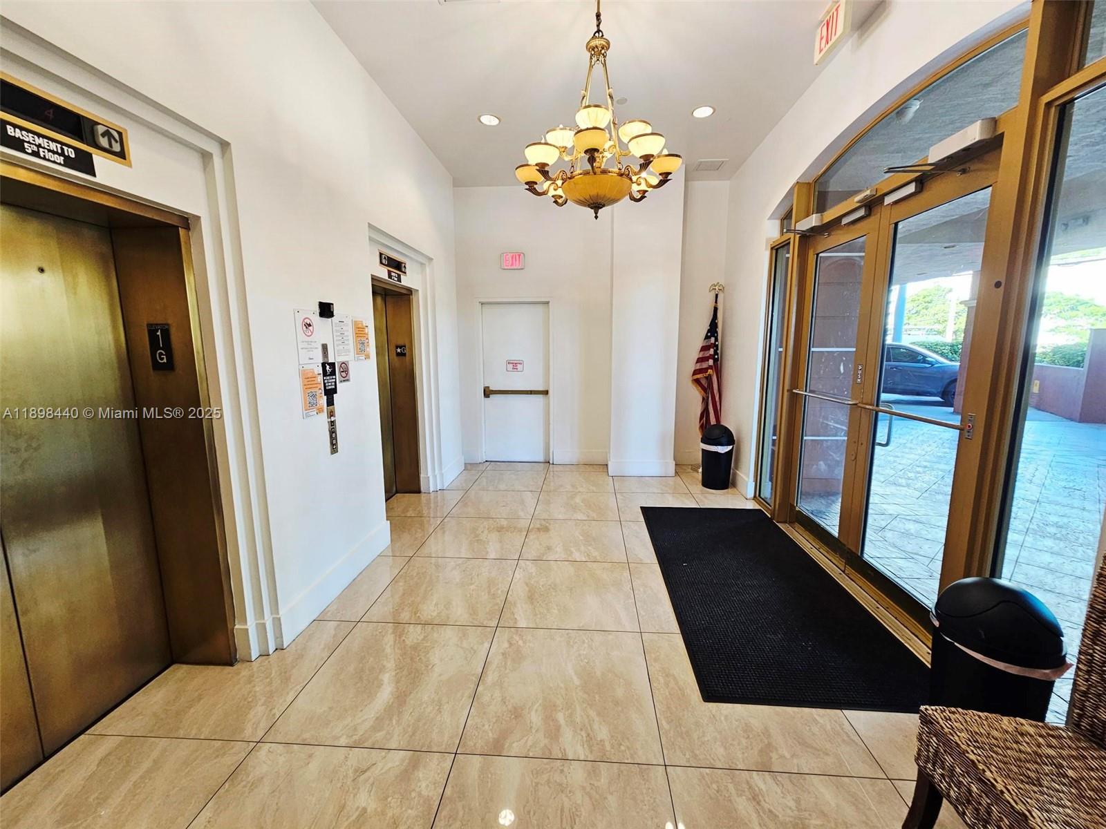 A building lobby features tile flooring, two elevators, a chandelier, and glass entrance doors — 2280 SW 32nd Ave # 511, Miami FL 33145, MIAMI, FL